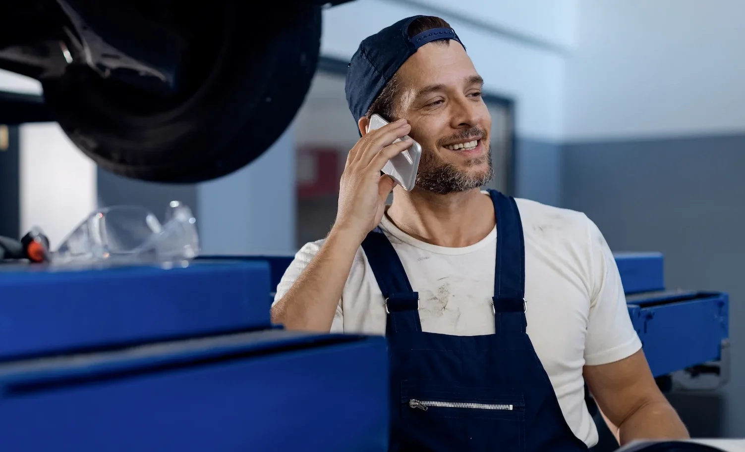 happy-mechanic-talking-phone-while-working-auto-repair-shop